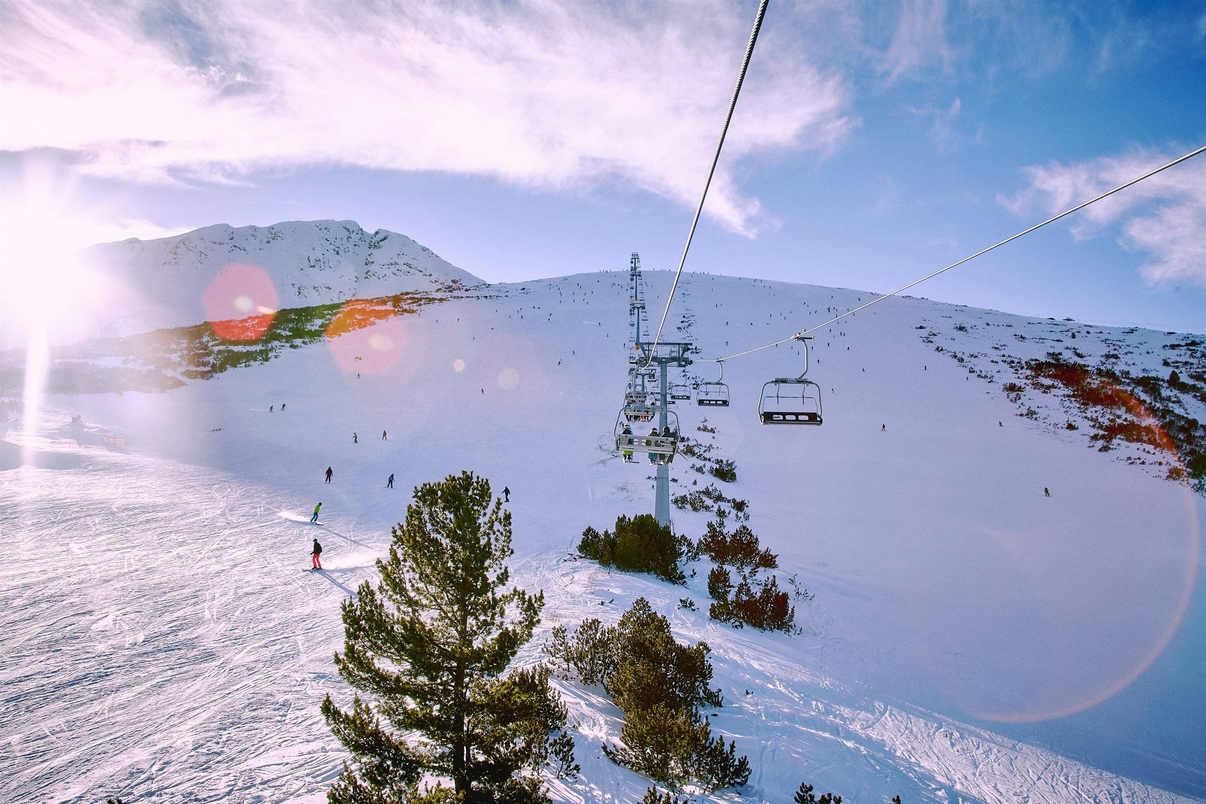 Skiers and chairlift on a sunlit Bansko piste